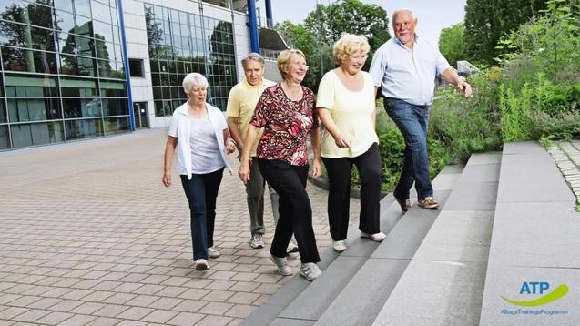 Gruppe &auml;lterer Menschen, die gemeinsam eine Treppe hinuntergeht, vor einem modernen Geb&auml;ude.