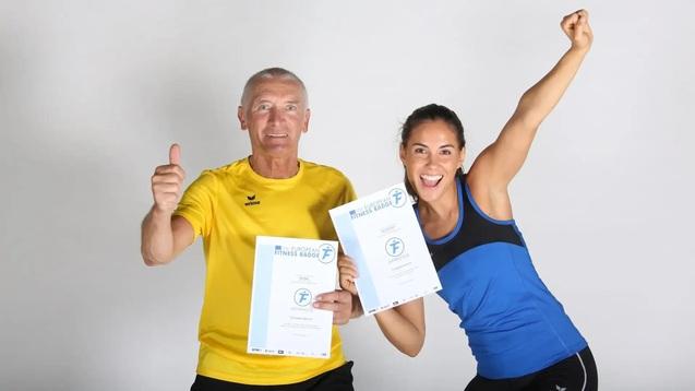 Zwei Sportler halten stolz ihre Urkunden in die Kamera und zeigen Freude, w&auml;hrend sie beide mit Daumen hoch posieren.